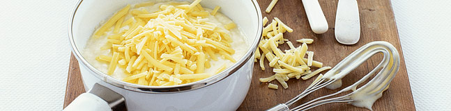 A bowl of cheese sauce toppe with grated cheese