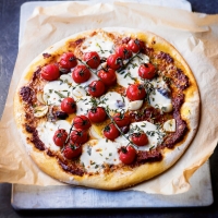 Pizza with mozzarella, rosemary, roasted tomatoes & black olives